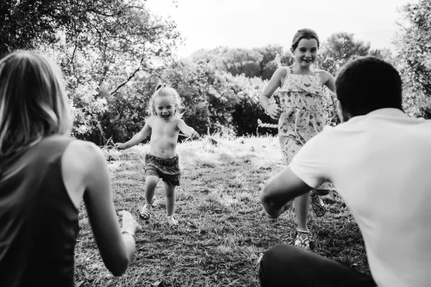 enfants qui courent dans les bras de leur parents en noir et blanc