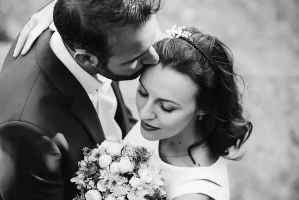 photo en noir et blanc du marié qui embrasse la mariée