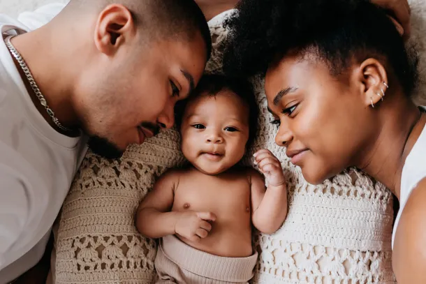 photo d'u bébé métis souriant entre ses parents