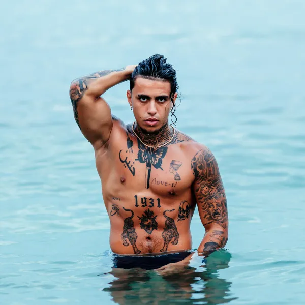 photo d'un modèle homme tatoué et torse nu qui sort de l'eau