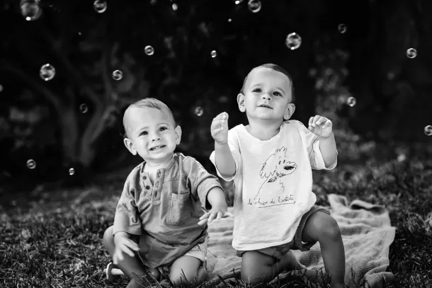 enfants jumeaux qui jouent avec des bulles en noir et blanc