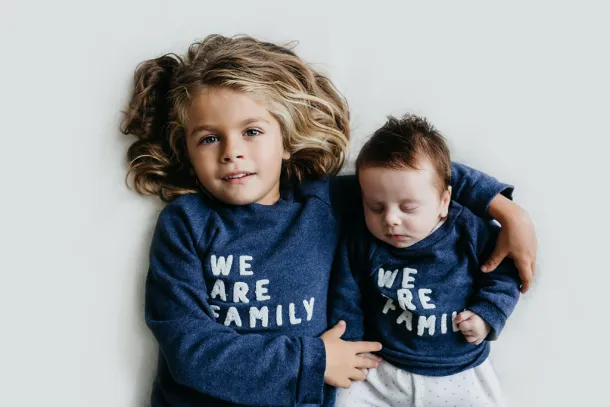 photo de naissance bébé dans le bras de son grand frère
