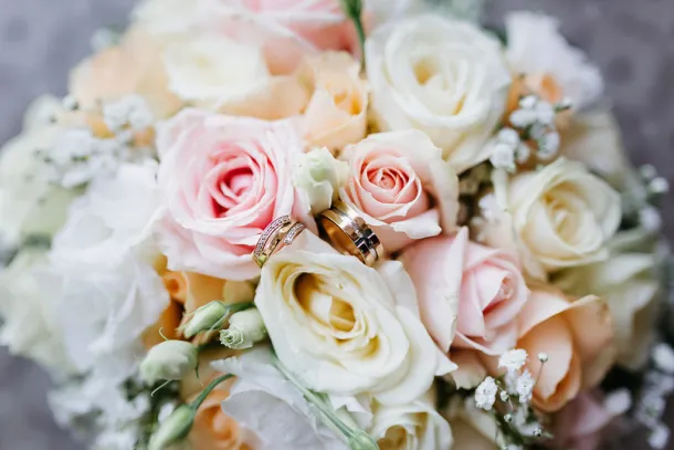 les alliances de mariage posées sur le bouquet rose et blanc de la mariée