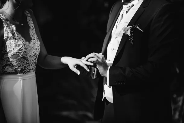 photo en noir et blanc du marié qui passe l'alliance à la mariée