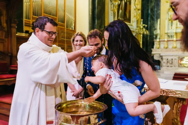 enfant qui pleure pendant que le prêtre le baptise