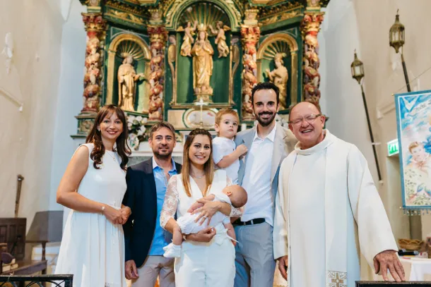 photos de famille et du prêtre devant l'autel à la fin d'un baptême à Paris
