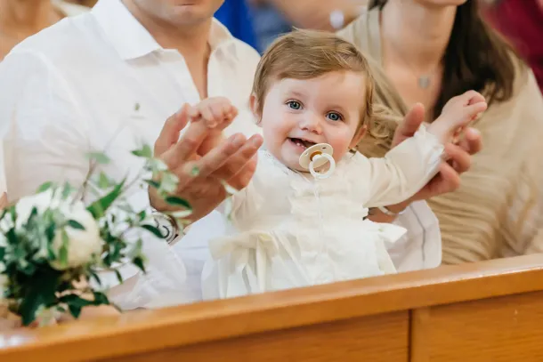 enfant sur les genoux de ses parents pendant son baptême